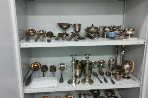 Silberne und goldene antike Besteck- und Trinkgefäße in einem Museumsschrank.