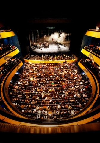 Ein vollbesetztes Opernhaus mit Bühne und Publikum, bei 