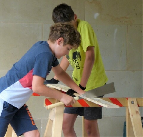 Ein Junge und ein Mädchen bauen ein Holzprojekt an einem Arbeitstisch im Museum.
