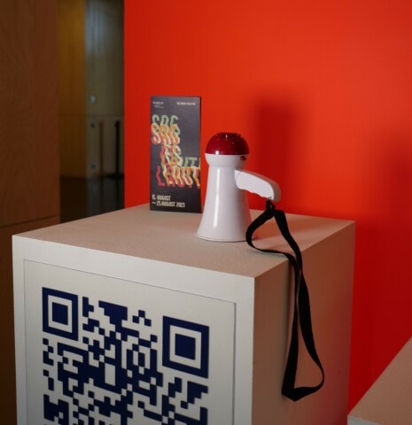 Interaktives Exponat mit QR-Code und rotem Sensor im Museum.