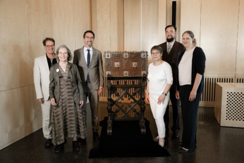 A group of people standing in front of a wooden chest.
