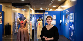 Zur Seite der Veranstaltung - Frau bei einer Führung im Museum vor historischen Ballettkostümen, Stuttgart.
