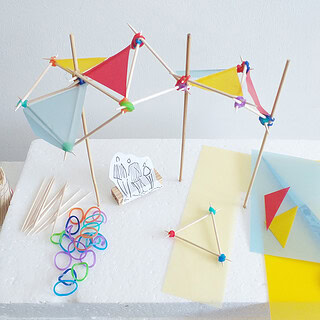 Bunte Sonnenschirme aus Papier und Holzstäbchen, Bastelmaterialien auf Styroporplatte.