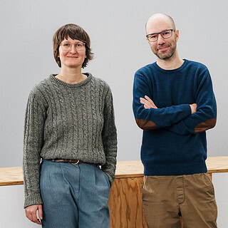 Zwei Personen stehen vor einer Holzbarriere im Museum für Stuttgart.