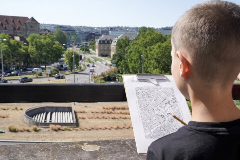 Junge mit Stadtplan auf Balkon mit Blick auf Stuttgart.